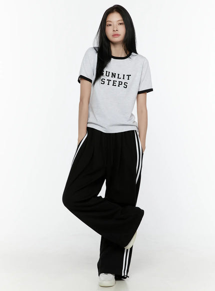 Stripe Detail Sweatpants IL506 Black front full-body model shot, standing pose styled with grey ringer tee, wide-leg track pants with white side stripes