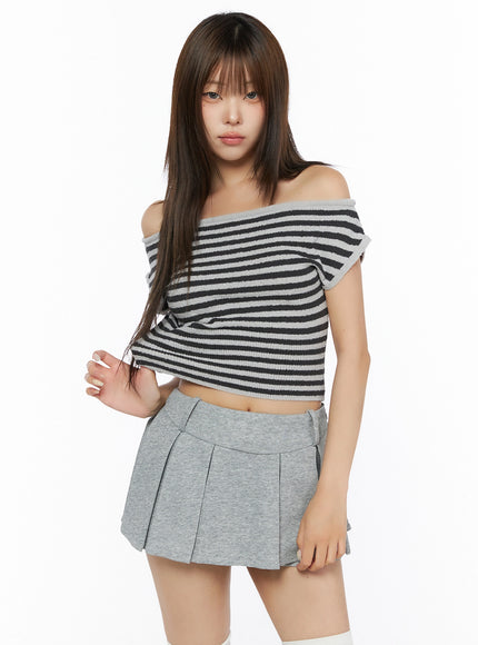 Stripe Off-Shoulder Knit Top IL506 Gray front close-up on model looking down, hand on hip, showcasing off-shoulder neckline and cropped hem with gray and black stripe knit texture