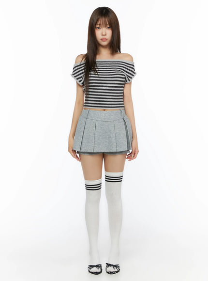 Stripe Off-Shoulder Knit Top IL506 Gray full-body front view on model standing straight, arms at sides, gray and black striped off-shoulder crop top with gray pleated skirt and white knee-high socks