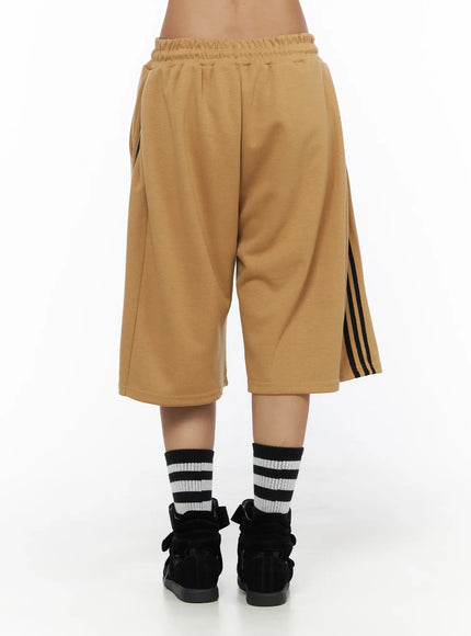 Striped Bermuda Shorts CL503 Beige back view on model showing clean back panel, black side stripe detail and loose boxy cut with striped socks and sneakers