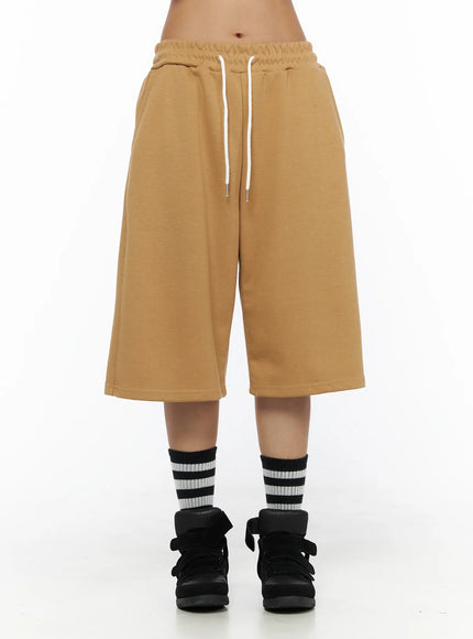 Striped Bermuda Shorts CL503 Beige front close-up on model showing white drawstring elastic waistband, wide-leg cut and clean front panel with striped socks and black sneakers