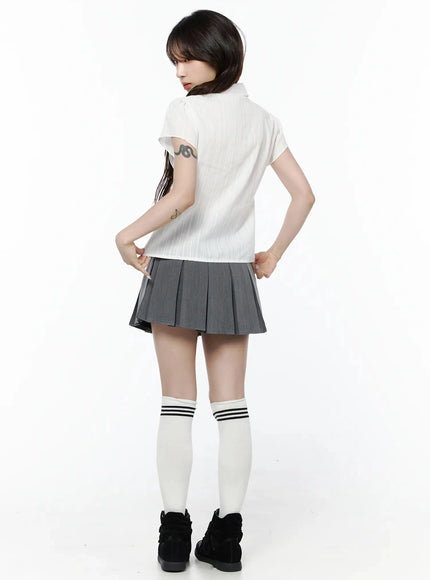 Striped Button-Up Blouse IL506 White full-body back shot on model with hands on hips showing rear striped texture, collar, and short sleeve detail with gray pleated skirt
