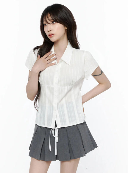 Striped Button-Up Blouse IL506 White front shot on model with hand on chest highlighting collar, button detail, fitted corset-style waist, and semi-sheer striped fabric