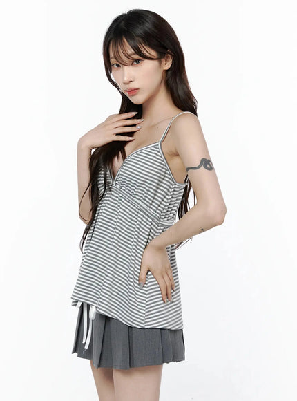 Striped Cami Tank Top IL506 Gray side shot on model with hand at neck, showing diagonal stripe drape, flared hem, and spaghetti strap silhouette