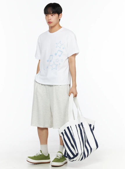 Striped Canvas Tote Bag IL514 Dark blue front shot on male model holding handles with both hands, oversized navy stripe canvas tote resting on ground, white tee styling