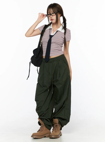 Striped Collared Crop Top Tee CL514 Pink full-length front shot on model with glasses adjusting frames, navy tie accessory, black mesh bag, and green parachute pants