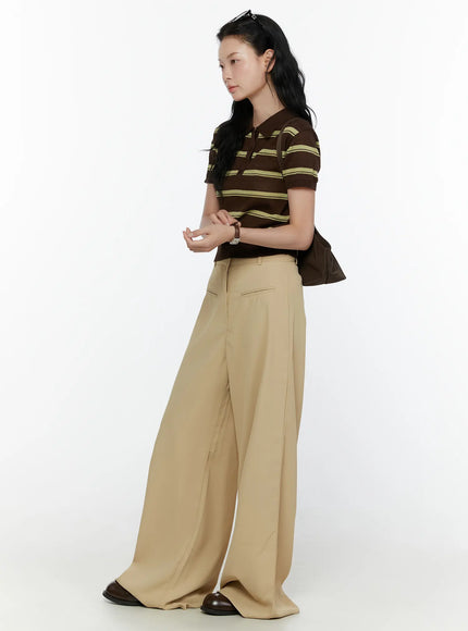 Striped Knit Polo Top CL520 Dark brown side shot on model hand raised to head angled pose showing cropped length and ribbed hem styled with beige wide-leg trousers