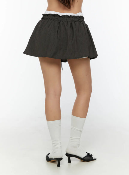 Striped Mini Skirt CU526 Dark gray back shot on model showing ruffled elastic waist, back drawstring, flared hem and pinstripe fabric with white knee socks and heeled sandals