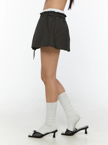 Striped Mini Skirt CU526 Dark gray side shot on model showing flared silhouette, ruffled waistband, side drawstring tie and pinstripe texture with white knee socks