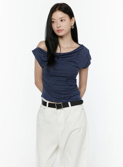 Striped Off-Shoulder Top IL506 Navy blue half-body front model shot with off-shoulder draped neckline, striped knit, styled with white pants and black belt