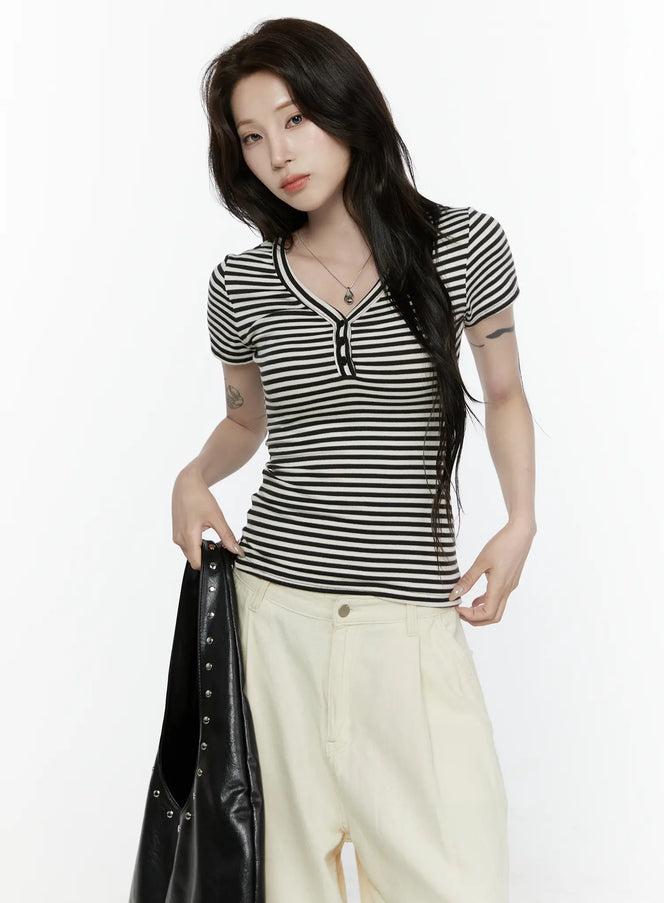 LEWKIN Striped Slim Tee IL521 White front view on model holding black leather jacket styled with cream wide-leg pants, short-sleeve ribbed henley