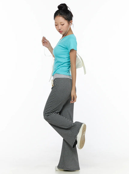 Striped Sweatpants CL513 black-gray side pose on model with leg raised showing wide flared hem and ribbed stripe knit fabric