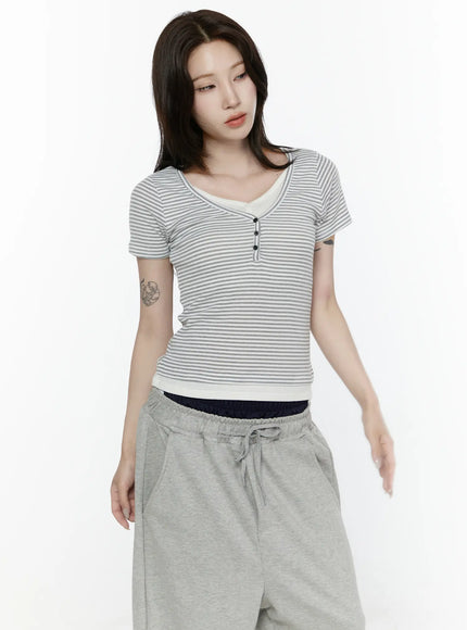 Striped T-Shirt IL522 White half-body front shot on model looking down, close-up of V-neck with layered cream inner trim and three black henley buttons on ribbed stripe fabric
