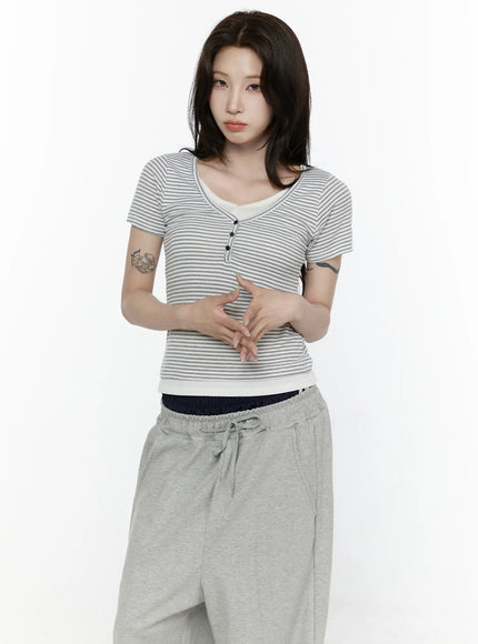 LEWKIN Striped T-Shirt IL522 White S/M front shot on model with hands clasped, fitted ribbed stripe tee with henley buttons and cream contrast trim, styled with gray sweatpants