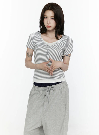 LEWKIN Striped T-Shirt IL522 White S/M front shot on model with hands clasped, fitted ribbed stripe tee with henley buttons and cream contrast trim, styled with gray sweatpants