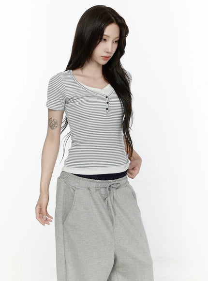 Striped T-Shirt IL522 White three-quarter front shot on model gazing down with one hand on hip, slim-fit striped henley tee with cream V-neck trim, tucked slightly over navy waistband