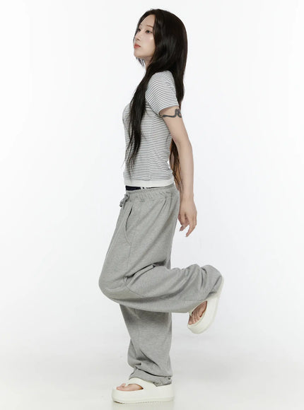 Striped T-Shirt IL522 White side shot on model with one leg raised, slim-fit striped short-sleeve tee with cream contrast hem band, side silhouette showing fitted ribbed knit texture