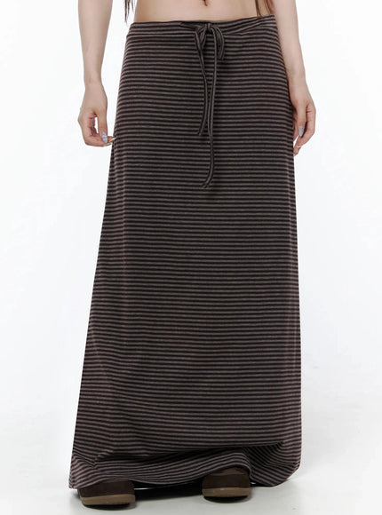 Striped Tie Maxi Skirt IL506 Brown front view on model without top layer, showing drawstring tie waist and full brown-black stripe maxi skirt