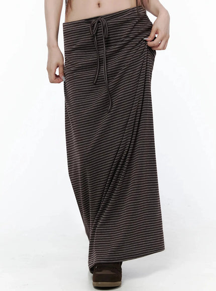 Striped Tie Maxi Skirt IL506 Brown front close-up on model showing gathered fabric at hip, drawstring tie, and full maxi length silhouette