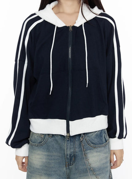 Striped Track Hoodie CL524 Dark blue close-up front detail shot on model, center zip, white drawstring hood, double white sleeve stripes, contrast ribbed waistband and cuffs