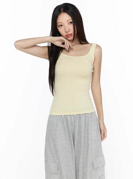 Striped U-Neck Tank Top CL524 Yellow front shot on model with hand raised to face showing slim fit ribbed fabric styled with gray cargo pants