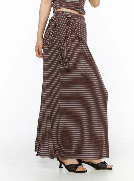 Striped Wrap Maxi Skirt CL502 Brown side view on model showing draped side-tie knot waist detail flared hem and black kitten heel sandals