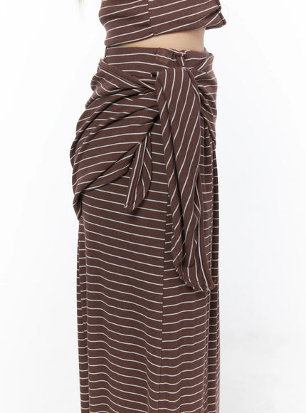 Striped Wrap Maxi Skirt CL502 Brown close-up side detail showing voluminous draped tie knot gathered fabric and ribbed stripe texture at hip on model