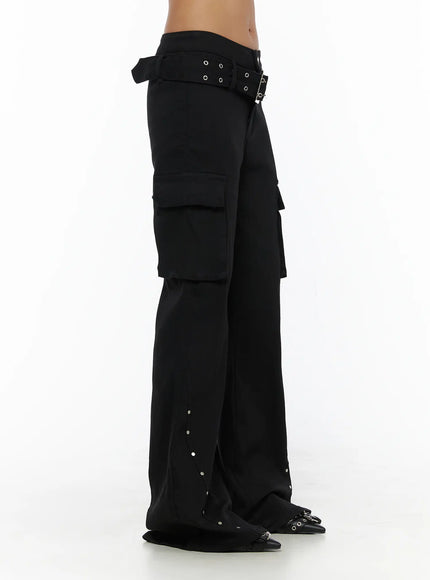 Studded Bootcut Pants CL503 Black side close-up on model showing grommet belt buckle detail, cargo pocket depth, and silver stud hem trim