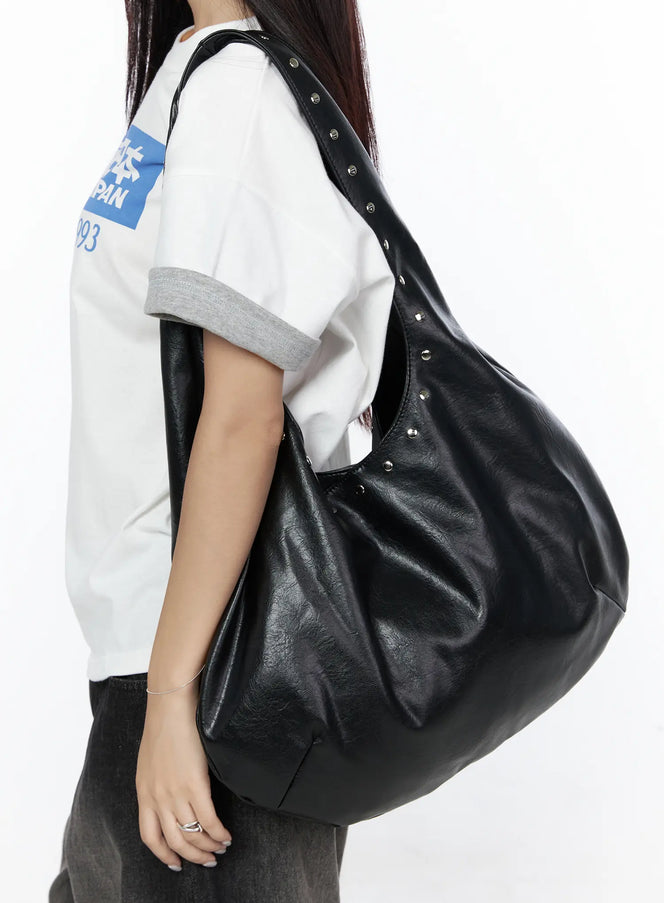 LEWKIN Studded Large Hobo Bag CL527 Black side view on model wearing white graphic tee and dark pants, slouchy faux leather shoulder bag with silver studs