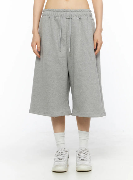 Studded Sweatshorts CU530 Gray front view on model cropped at waist showing wide-leg cut drawstring tie elastic waistband fleece sweatshort with white sneakers
