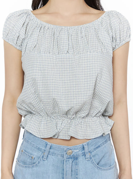 Summer Plaid Off-Shoulder Blouse IU525 Light blue detail close-up on model showing gathered elastic neckline, puff cap sleeves, ruffle hem, and check pattern