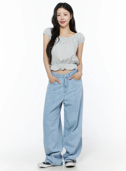 Summer Plaid Off-Shoulder Blouse IU525 Light blue front view on model smiling with hands in pockets styled with wide-leg denim and sneakers