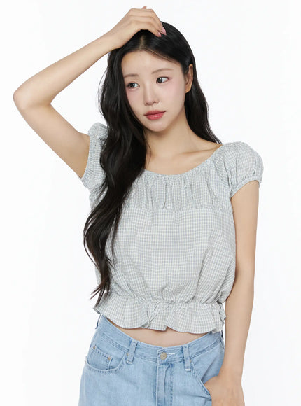 Summer Plaid Off-Shoulder Blouse IU525 Light blue close-up front on model with hand in hair showing gathered square neckline and gingham check fabric texture