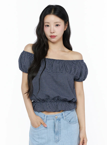 Summer Plaid Off-Shoulder Blouse IU525 navy blue front view on model wearing off-shoulder style with puff sleeves and elastic ruffle hem paired with light jeans