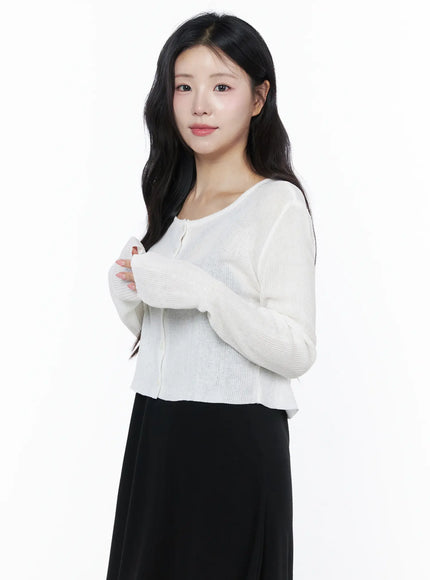 Summer Ribbed Crop Cardigan IU525 White side-angle close-up on model with arms crossed showing ribbed texture sheer knit fabric and fitted crop silhouette