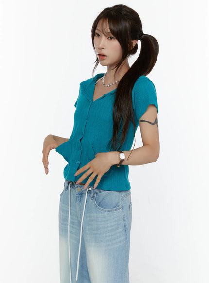 Summer Short Sleeve Hooded Knit Cardigan CL507 Teal half-body side-angle front shot on model pulling hem, pointelle knit texture with button placket and hood detail in blue-green color