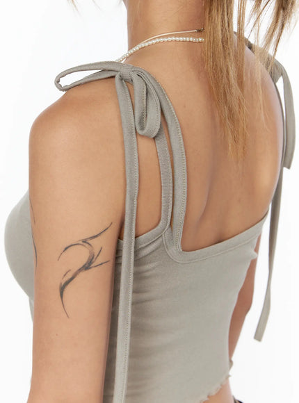 Tie-Front Studded Cami CU524 Beige close-up detail of shoulder tie strap showing knotted fabric ribbon ribbed knit texture and back neckline construction on model