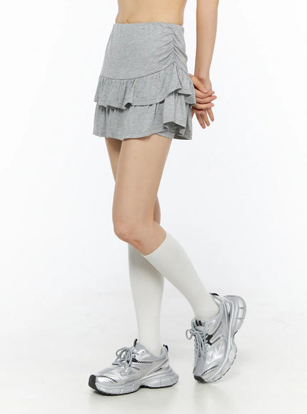 Tiered Flare Mini Skirt CU530 Gray side shot on model with hands clasped, highlighting ruched waistband and layered ruffle hem with white knee socks