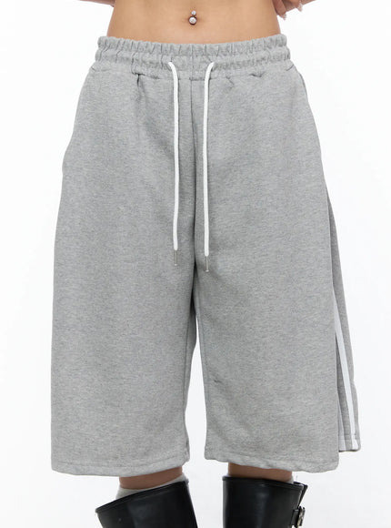 Track Bermuda Shorts CU523 Gray front close-up detail on model showing white drawstring, elastic waistband, side white stripe, and heathered fleece texture