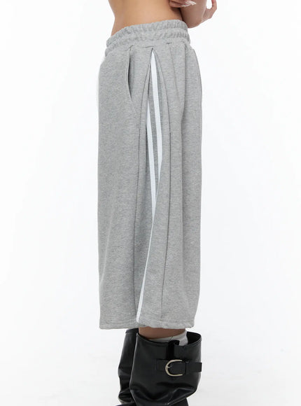 Track Bermuda Shorts CU523 Gray side detail close-up on model without boots showing pleated waistband, white side stripe panel, and wide-leg drape in fleece