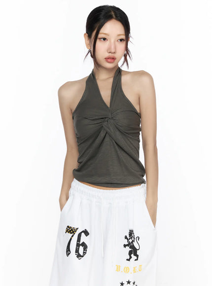 Twist Halter Top CL524 khaki green front close-up on model with V-neckline twist knot detail and soft draped jersey fabric paired with white wide-leg pants