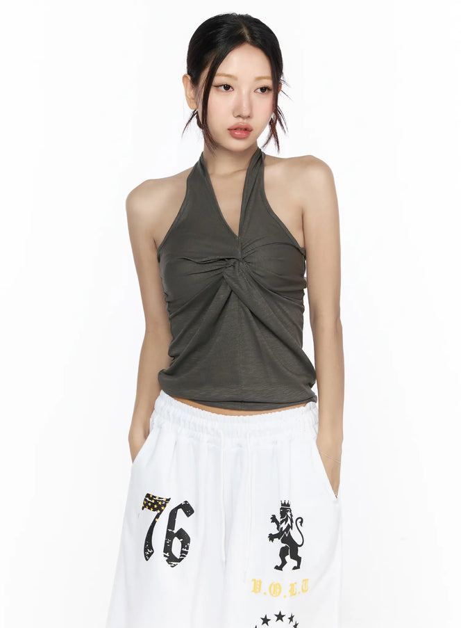 Twist Halter Top CL524 khaki green front close-up on model with V-neckline twist knot detail and soft draped jersey fabric paired with white wide-leg pants