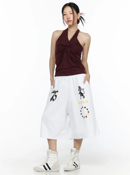 Twist Halter Top CL524 Dark red full-body front view on model standing with hands in pockets styled with white graphic wide-leg pants and white high-top sneakers