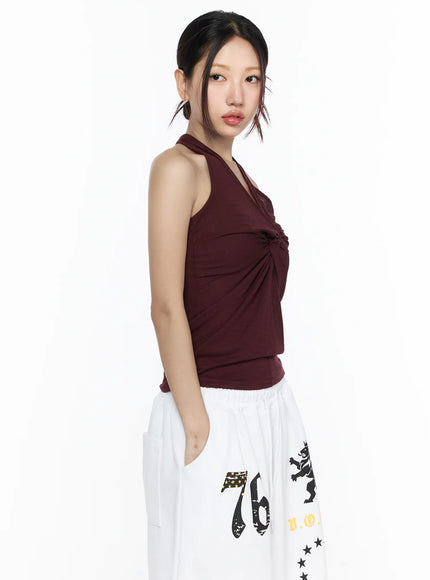 Twist Halter Top CL524 Dark red three-quarter side view on model facing left showing twist knot front detail and halter neckline with white graphic pants