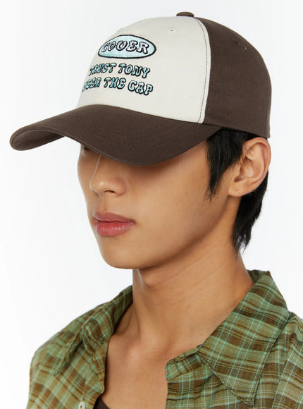 Two-Tone Graphic Cap IL515 Dark brown side model shot, male model facing left showing brown brim profile and cream front panel with partial embroidery