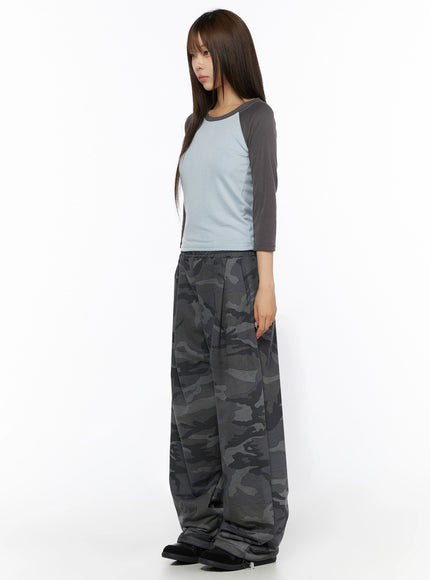 Two-Tone Long Sleeve Top IL523 Light blue side full-body shot on model facing left, showing charcoal raglan sleeve detail and cropped hem over camo wide-leg pants