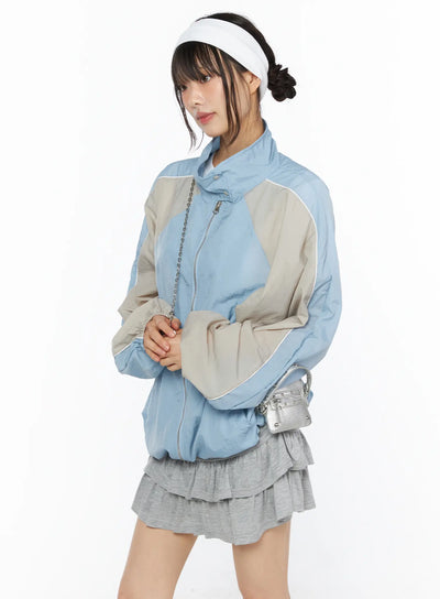 LEWKIN Two-Tone Oversized Windbreaker CU530 Light blue side shot on model wearing visor headband and gray ruffle mini skirt with silver chain bag