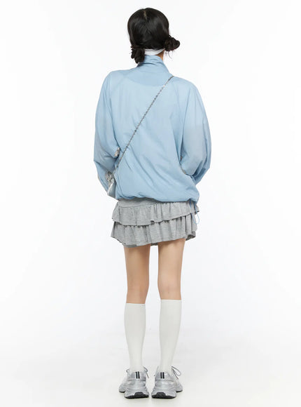 Two-Tone Oversized Windbreaker CU530 Light blue full-length back shot on model with silver chain crossbody bag wearing gray ruffle skirt white socks silver sneakers