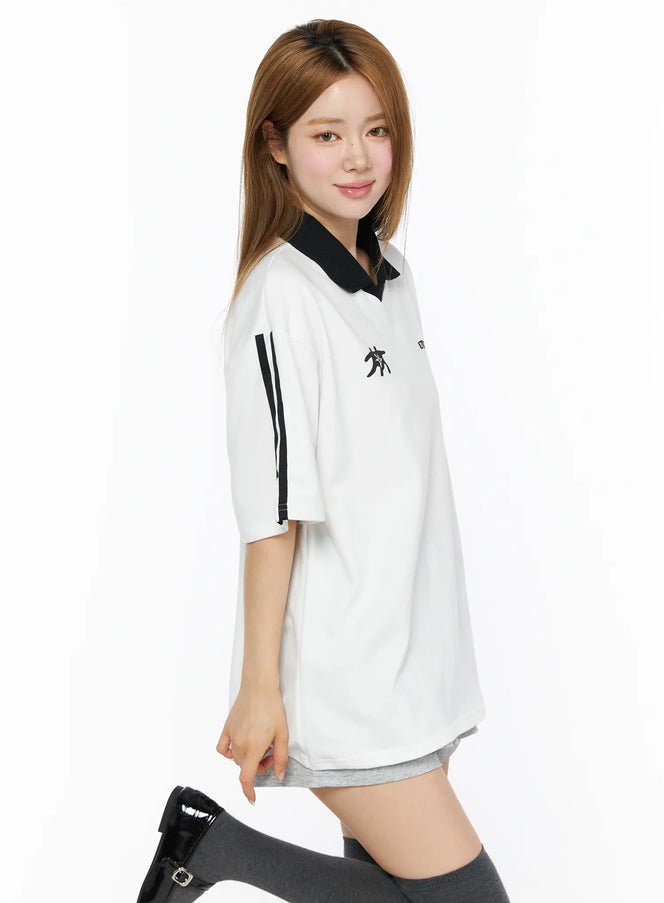 Two-Tone Relaxed-Fit Polo Shirt CL502 White side shot on model smiling with black collar stripe details on sleeve paired with grey shorts and patent knee boots