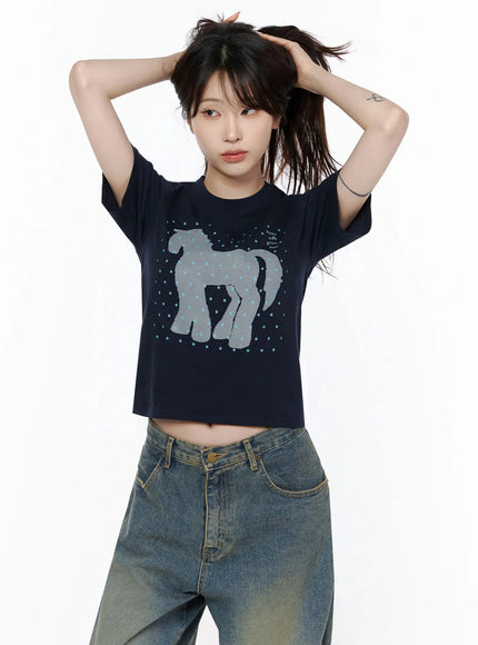 Unicorn Graphic Crop T-Shirt IL506 Navy blue front model shot arms raised hands in hair showing horse star graphic crop fit styled with wide-leg jeans